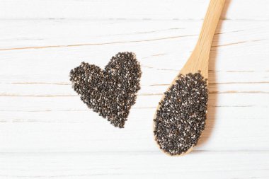 Tahta kaşık beyaz arka plan üzerinde kalp ve chia tohum