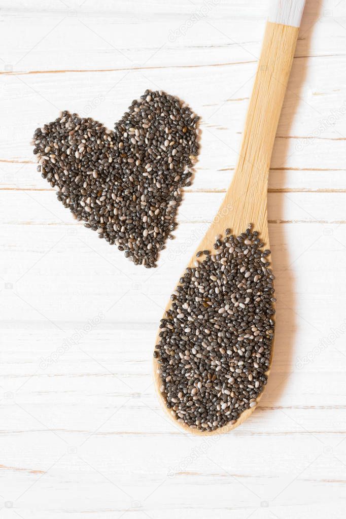 Heart and chia seeds in wooden spoon on white background. Healthy food