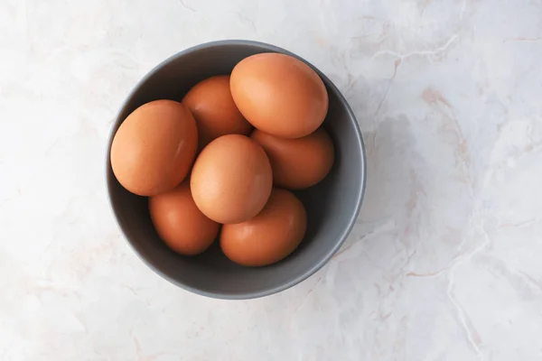 Beyaz mermer masa üzerinde gri kasede taze tavuk yumurtası. — Stok fotoğraf