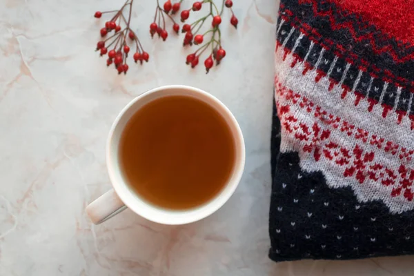 Chá de ervas em xícara branca, suéter de malha e bagas vermelhas em marb — Fotografia de Stock