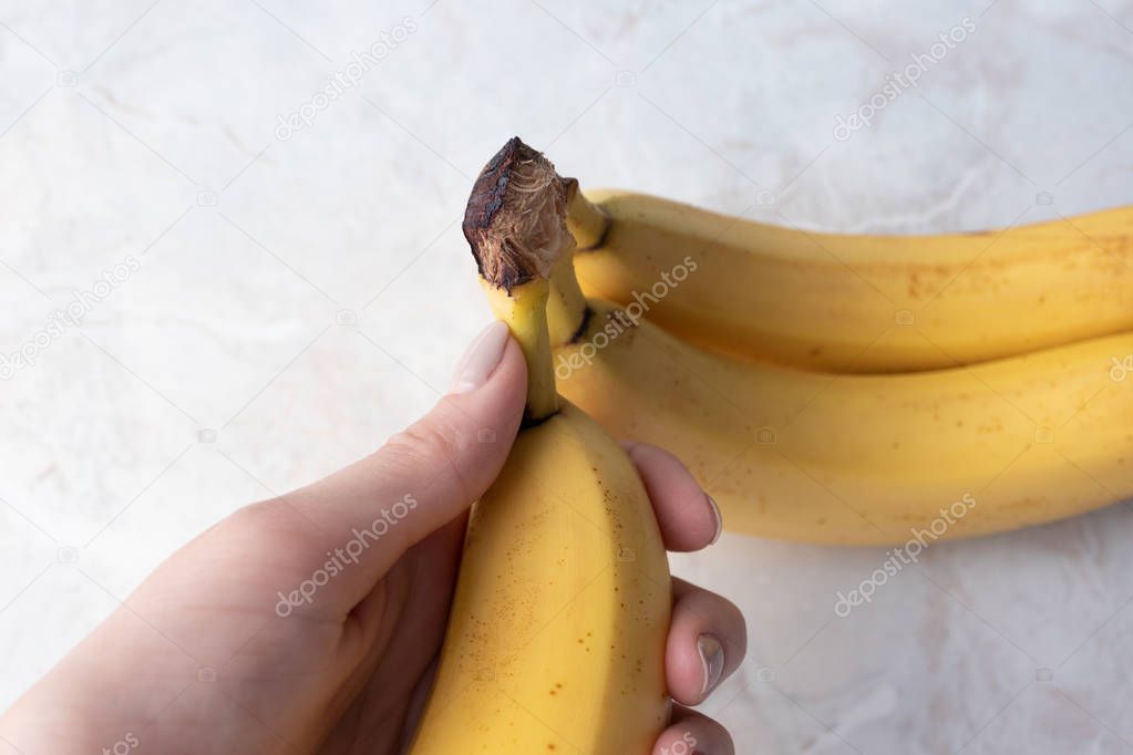 Woman takes one fresh banana. Female hand holding yellow ripe ba
