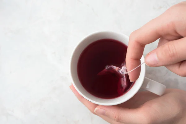 Mujer haciendo té afrutado en bolso pirámide de té en taza blanca en marbl — Foto de Stock