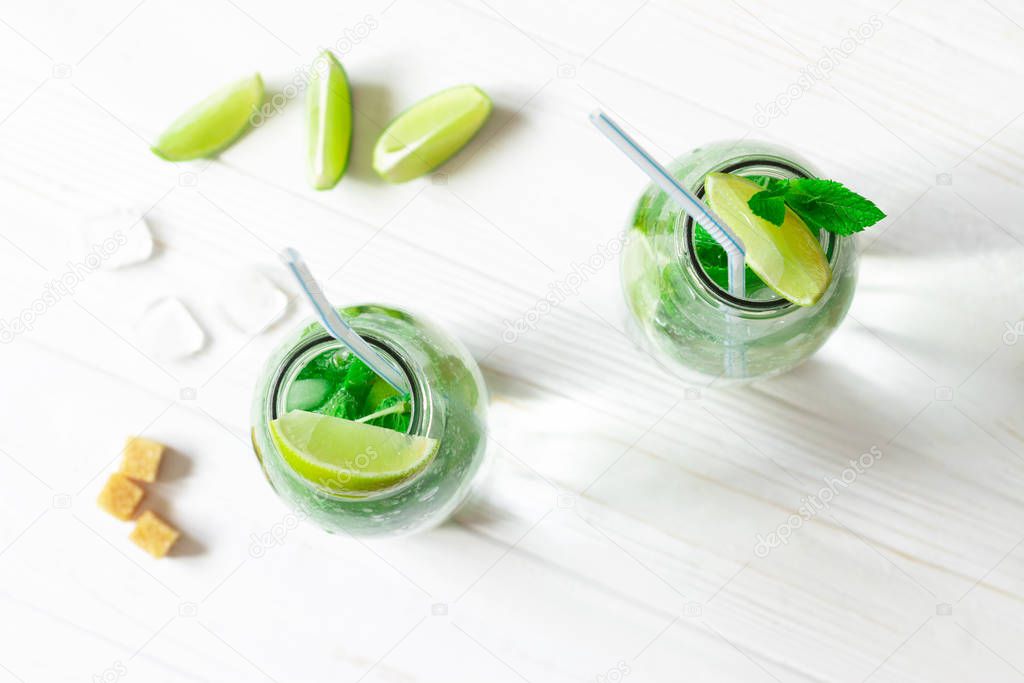 Mojito in glass jar on white wooden background and cube of ice, 