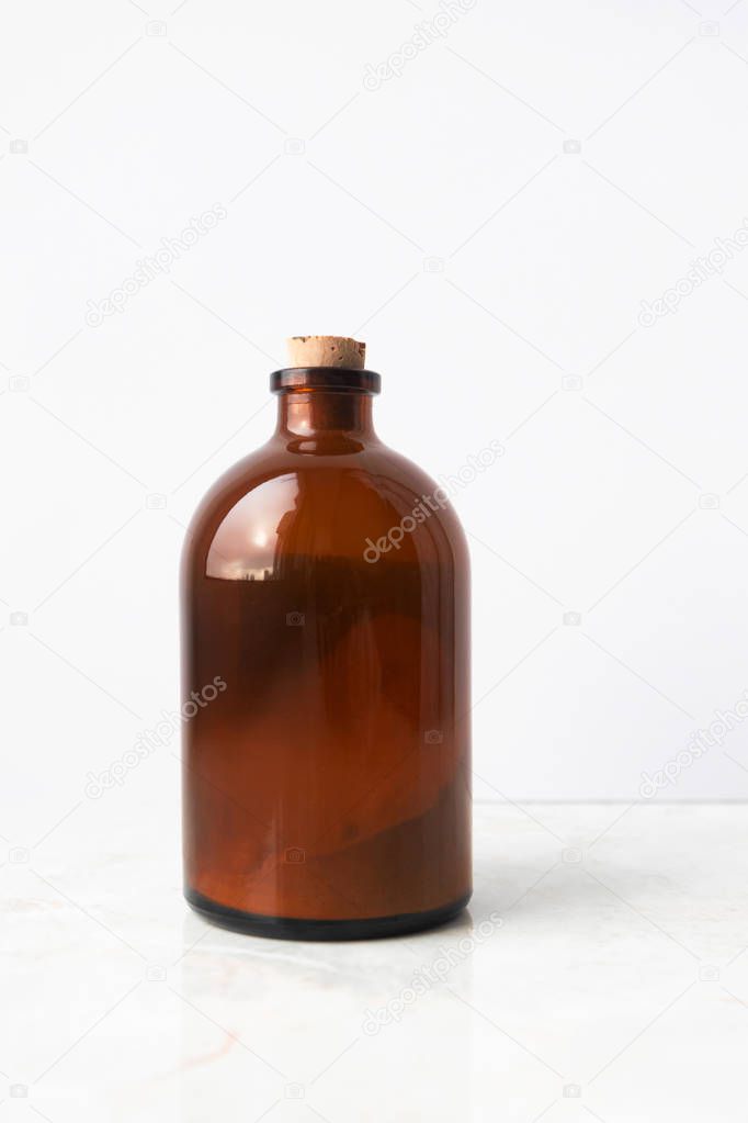 Glass brown bottle with organic ubtan powder on white background
