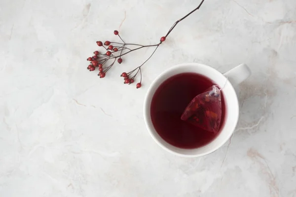 Thé fruité en sachet pyramidal en tasse blanche et baies rouges sur ma — Photo