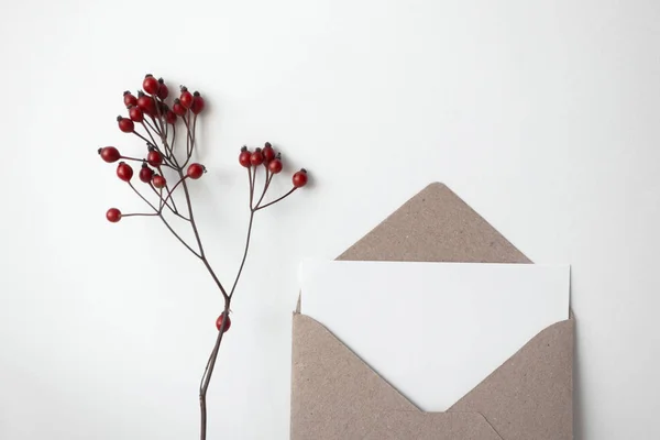 Ambachtelijke papieren envelop met lege witte wenskaart en rode berr — Stockfoto