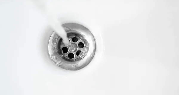 Água em drenos de pia de cerâmica branca para baixo, de perto — Fotografia de Stock