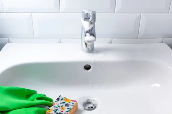 Keramiska tvättställ med gröna gummihandskar och gul svamp, cl — Stockfoto