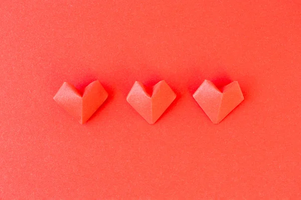 Орігамі серця на фоні червоного паперу, вид зверху. 14 лютого — стокове фото
