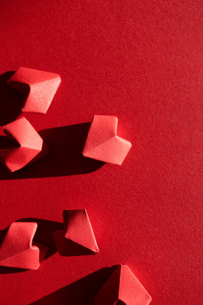 Paper origami hearts on red background top view with copy space