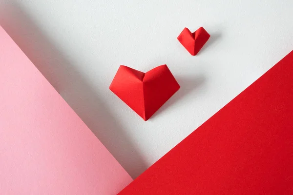 Dois corações de origami em fundo branco e rosa e vermelho papel bo — Fotografia de Stock