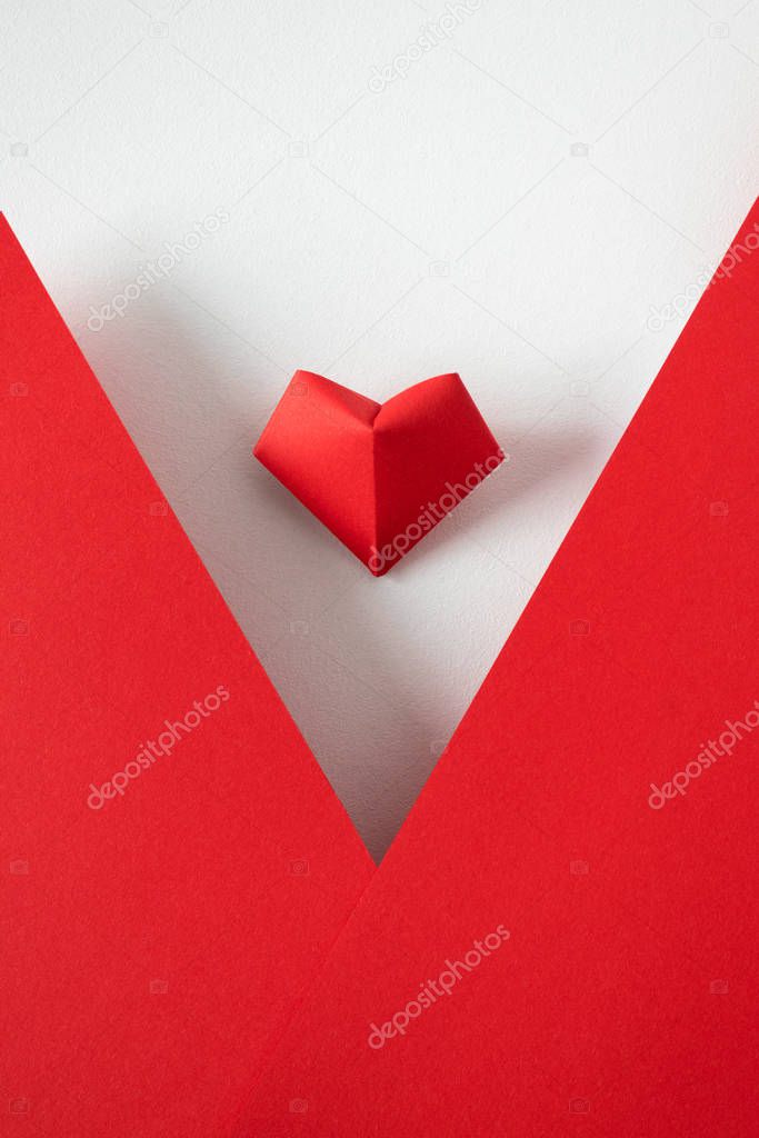 Heart origami on white background and red paper frame, top view.