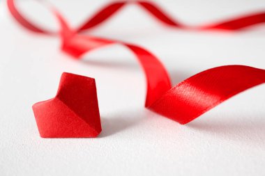 Ön planda beyaz arkaplanda Origami kalp ve saten bantlar.