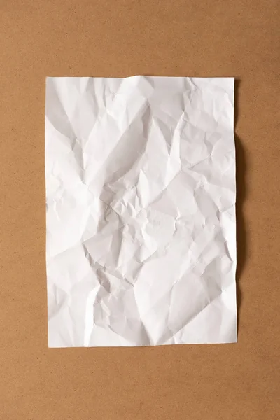 Hoja de papel blanco arrugado sobre fondo de cartón. Parte superior vi — Foto de Stock