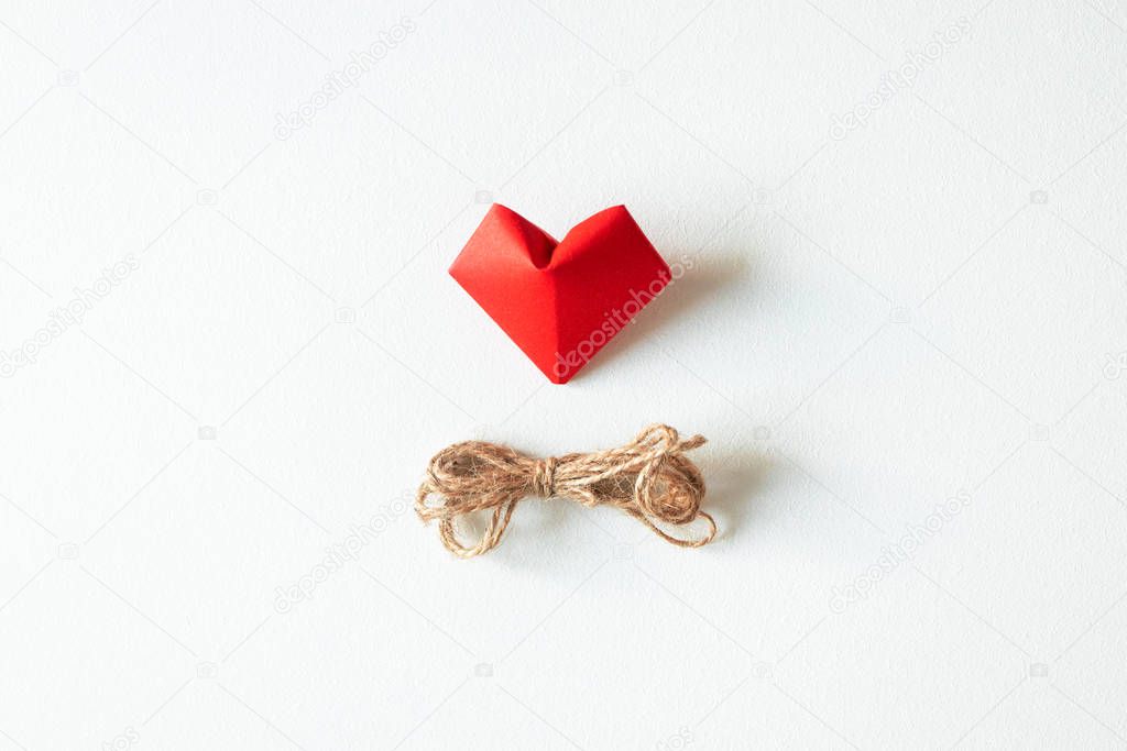 One red origami heart shape and rope twine isolated on white bac