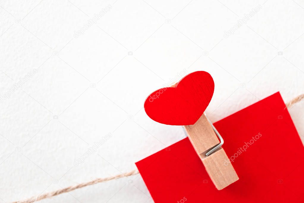 Close-up red heart wooden clothespin on rope twine on white wall