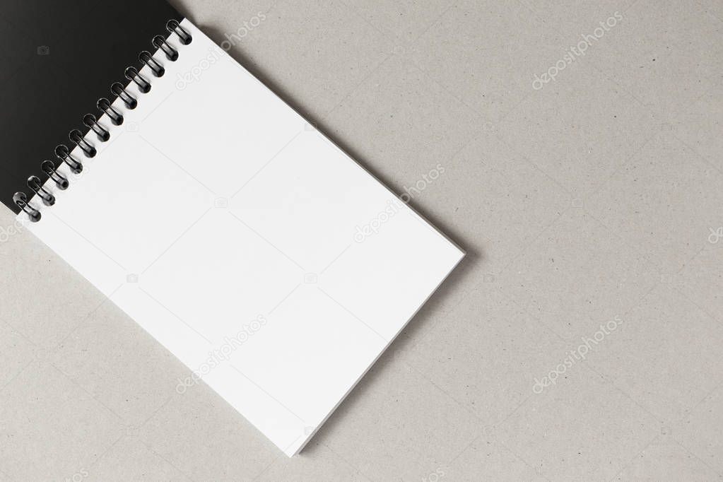 Open notebook with blank white paper sheet and copy space on gra