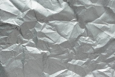 Buruşmuş gümüş folyo folyo dokusu. Soyut gri kırışık yaprak deseni, üst görünüm