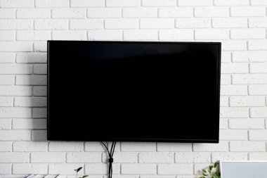 Beyaz duvarda, kapalı alanda siyah bir televizyon var. Oturma odası. Evde dinlenme kavramı
