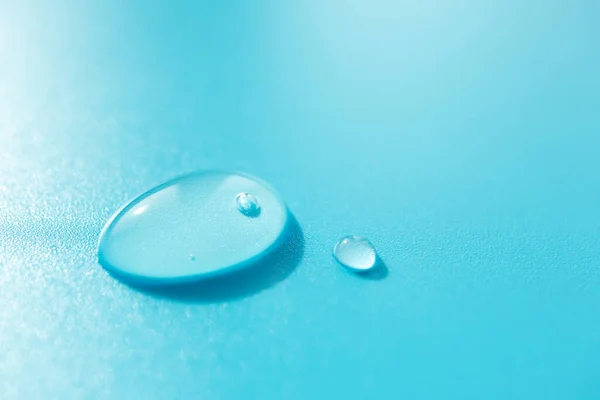 Hava kabarcığı olan makro su damlaları ve mavi arkaplanda kopyalama alanı; ön görüş. Yakın çekim nemlendirici ve cilt bakımı; dikey