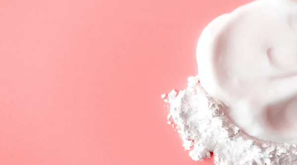 Cilt kremi ve pembe arka planda beyaz şeffaf yüz pudrası, fotokopi alanı, üst manzara. Kirli kozmetik doku. Güzellik pankartı biçimi