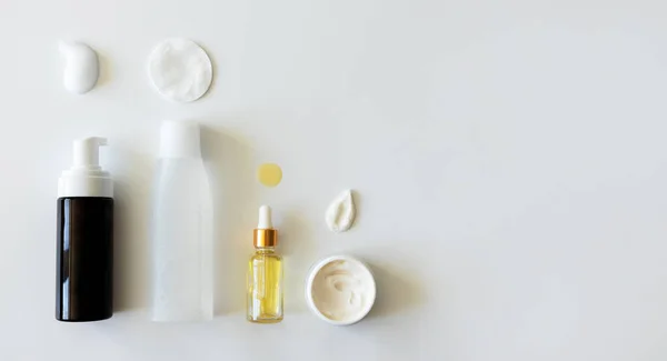 Temizleyici köpük, tonik ve pamuk pedi, yağ serumu özü damlası ve nemlendirici leke. Beyaz arka planda sahte şişeler. Yüz bakımı için güzellik ürünleri, yukarıda