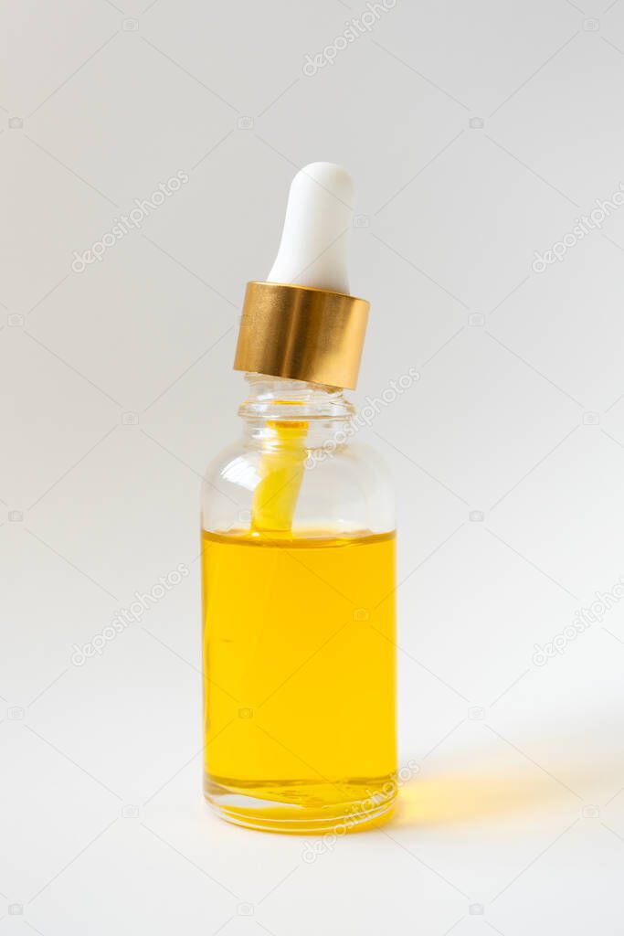 Close-up oil vitamin serum in glass bottle on light background. Skincare beauty product, vertical