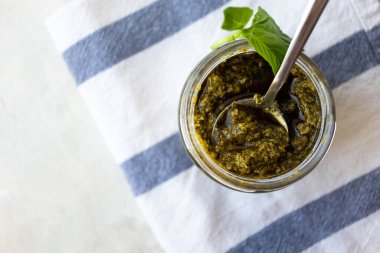 Mutfak havlusunda kaşık içinde fesleğen sosu. İtalyan sosu 