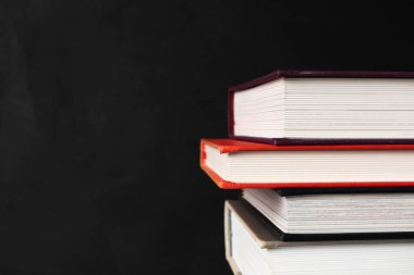 Kopya alanı olan siyah arkaplan üzerine seçici odaklı kitap yığını. Sancak biçimi. Evde eğitim, öğrenim ve öğrenim