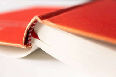 Kırmızı kapaklı, beyaz arkaplan üzerine seçici bir odaklanma içeren kapalı bir kitap. Eğitim, öğrenim ve öğrenim