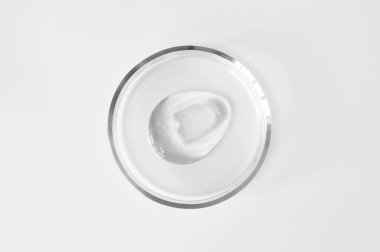 Beyaz arka planda cam petri kabında şeffaf aloe jeli lekesi. Laboratuvar testleri ve araştırmalar, kozmetik üretimi. Saf yüz temizleyici, kabuk soyucu, şampuan veya duş jeli.