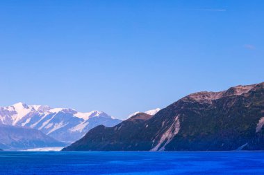 Alaska Cruise 'dan Buzul Körfezi Ulusal Parkı' na, gemiden dağlara manzaralı bir manzara. Güneşli hava, deniz, karlı uçurumlar ve tepeler. Alaska 'nın İçinden.