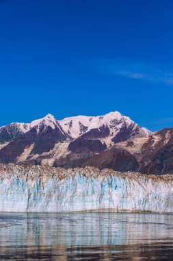 Alaska Cruise 'dan Buzul Körfezi Ulusal Parkı' na, gemiden Buzul 'a yakın çekim görüntüsü. Güneşli hava, sakin deniz, karlı uçurumlar ve tepeler. Alaska 'nın içinde Johns Hopkins Buzulu.