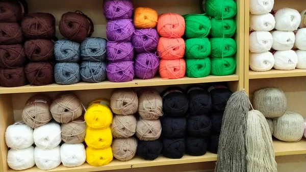Mağazanın raflarında iplik derileri var. Örgü örmek için iplik yumağı. Renkli iplikler raflarda..