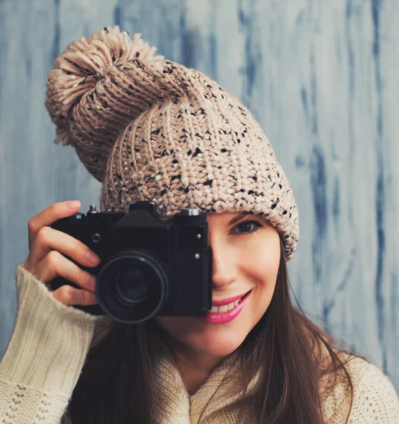 Pretty young woman in hat with vintage camera