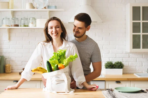 Young couple in kitchen with food bag, caucasian man and woman together, lifestyle concept, copy  space