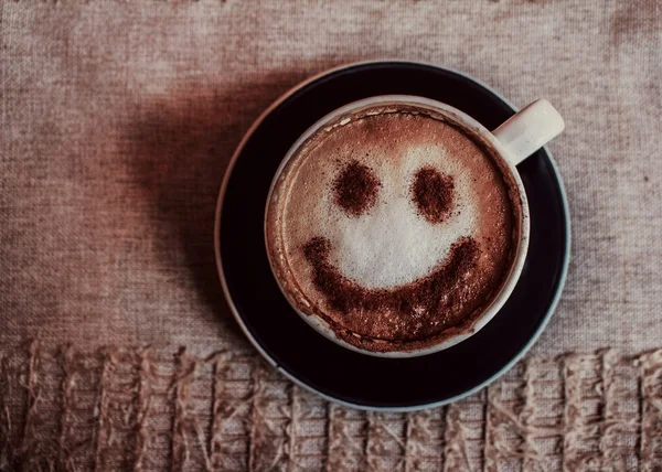 Фото чашки кофе капучино на тарелке с отпечатком улыбки на пене на салфетке — стоковое фото