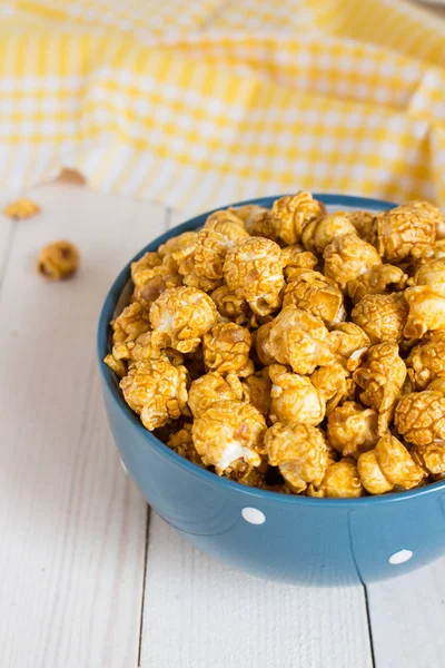 Caramel popcorn in cup on white wooden table — Stock Photo, Image