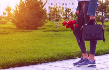 Jeans buket Lale çiçek ve çanta ile genç kız parkta yürüyor