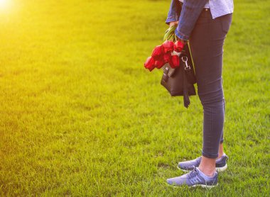 Jeans buket Lale çiçek ve çanta ile genç kız parkta yürüyor