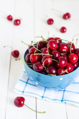 Beyaz ahşap zemin üzerine mavi havlu ıslak zeminde kırmızı kiraz