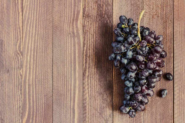 Чорна виноградна гілка на темному дерев'яному фоні — стокове фото