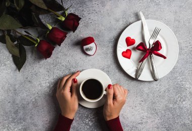 Kahve tutan Sevgililer günü romantik yemek masası ayarı kadın el