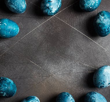 Çerçeve koyu zemin üzerine mavi renkli el tarafından boyalı Paskalya yortusu yumurta