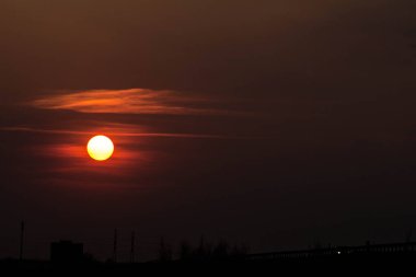 Gün batımında yol kenarında. Gün batımında büyük kırmızı güneş. Günbatımı arka planında arabalar. Geçmişi. Doku.
