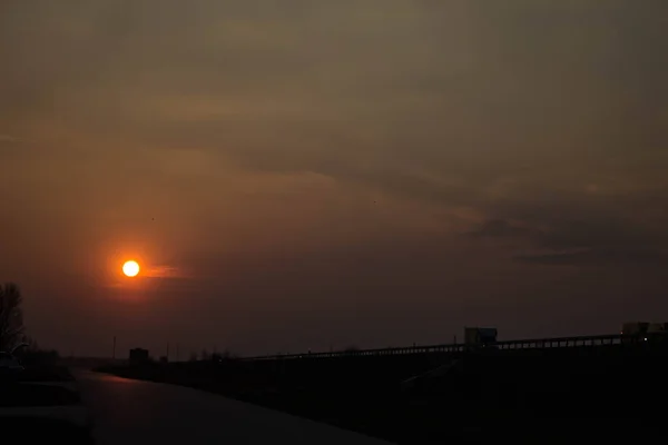 道路の近くの日没 日没の大きな赤い太陽 日没の背景に車 テクスチャ — ストック写真