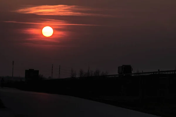 道路の近くの日没 日没の大きな赤い太陽 日没の背景に車 テクスチャ — ストック写真