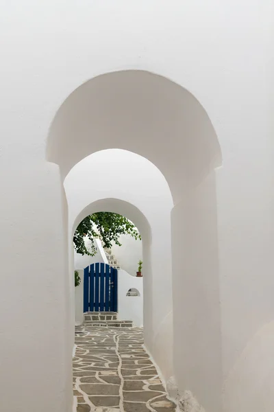 Gebogen deuren leiden naar een blauwe deur. Traditionele architectuur van lokale dorpen op het eiland Paros in Griekenland. — Stockfoto