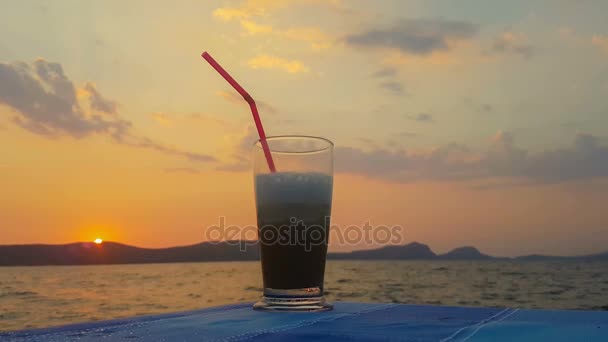 Ledová káva proti západu slunce a moře. Krásný klidný večer. — Stock video