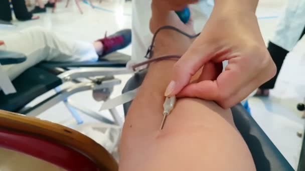 Infermiera che estrae l'ago della mano di un uomo che si offre volontario come donatore di sangue . — Video Stock